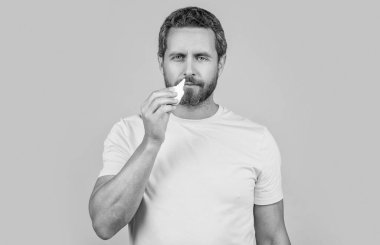 Adam stüdyoda burun tıbbı kullanıyor. Burun tıbbı damlaları olan bir adamın fotoğrafı. Burun tıbbı olan adam sarıda izole edilmiş. Geçmişinde burun tıbbı olan bir adam..