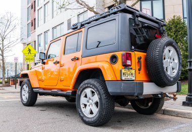 New York, ABD - 31 Mart 2024: 2012 Jeep Wrangler Sınırsız Sahra sarı arabası açık havada park edilmiş, nadir manzara.