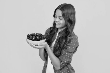 smiling teen girl hold cherry bowl on yellow background.