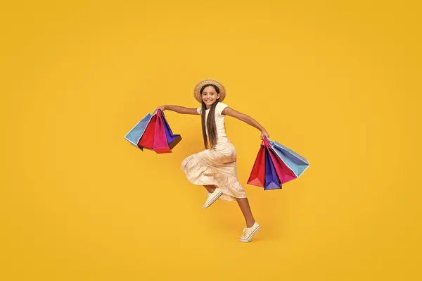 Fröhliche Teenie Mädchen Laufen Mit Einkaufstaschen Auf Gelbem Hintergrund Volle lizenzfreie Stockfotos
