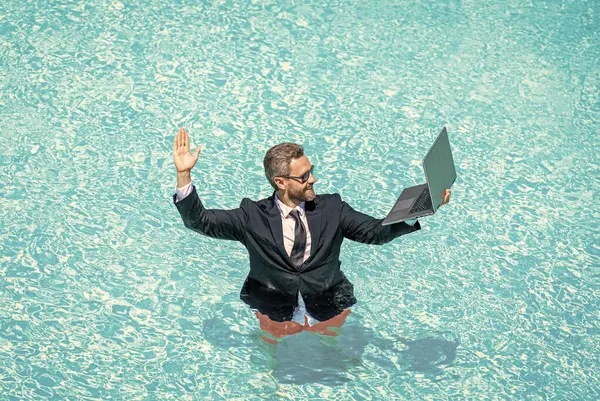 Summer business dreams. successful man. Businessman in suit with laptop in swimming pool. business man on summer vacation. businessman in wet suit in swim pool. Remote working. Crazy summer.