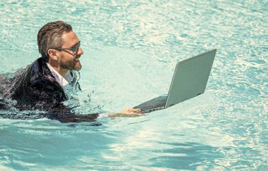 Yüzme havuzunda dizüstü bilgisayarı olan iş adamı. Yaz tatilindeki iş adamı. Yüzme havuzunda dalgıç kıyafetli bir iş adamı. Uzaktan kumanda çalışıyor. Yaz iş hayalleri. Başarılı adam. iş hafta sonu.