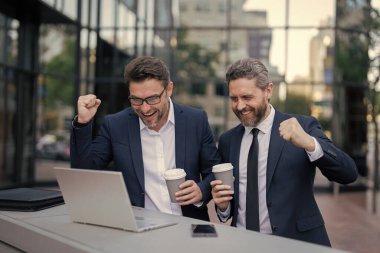 İki mutlu tüccar dışarıda dizüstü bilgisayarlarıyla serbest çalışıyorlar..