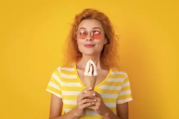 stock image smiling girl with cone icecream in studio. girl with cone icecream on background. photo of girl with cone icecream at summer. girl with cone icecream isolated on yellow.