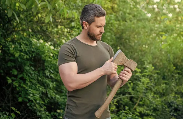 stock image man holding ax. man with ax wearing shirt. man with ax outdoor. photo of man with ax.