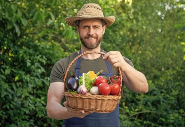 man in straw hat hold basket full of vegetables.
