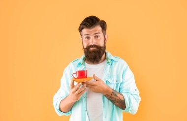 confused bearded guy hold morning coffee on yellow background, morning.