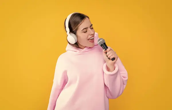 Positives Junges Mädchen Mit Kopfhörer Und Mikrofon Auf Gelbem Hintergrund lizenzfreie Stockbilder