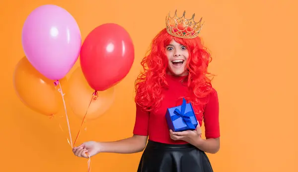 stock image happy child in crown with gift box and party balloon on yellow background. wow.