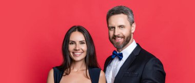 Çift poz veriyor. Kırmızıda izole edilmiş resmi kıyafetli zarif bir çift. Kadın ve erkek zaman zaman çıkıyorlar. Romantik aşk. Sevgililer Günü. Zarif giyimli bir çift. Resmi erkek ve kadın..