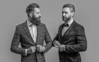 Smokin giyen moda adamları. Smokinli adamlar Griler 'de izole edilmiş. Smokinli adamlar stüdyoda. Smokinli adamlar arka planda.