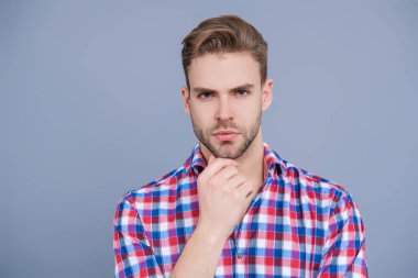 Erkek güzelliği ve saç stili. Gündelik giyinen milenyum adamı. Yakışıklı genç adam. Sıradan gömlekli bir adamın portresi. Gri üzerinde kollarını çapraz tutuyor. Tıraşsız erkek derisi. Sana şehvetli bakışlar atıyor..