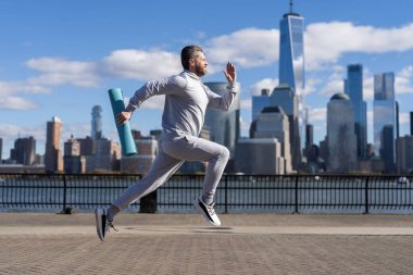 Sporcu adam aktif giyinmek için koşuyor. Sporcu koşucu. Manhattan 'da spor habercisi. New York 'a doğru koşan sporcu. Fiziksel aktivite.