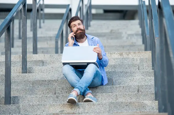 Adamın dış mekanda görüntülü iletişimi var. Adamın dışarıda çevrimiçi video bağlantısı var. Adamın merdivenlerde online video bağlantısı var. Adamın online video iletişimi var.