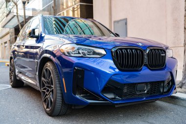 New York City, ABD - 25 Mart 2024: BMW X3 M parlak mavi araba dışarıda park halinde, köşe manzaralı.