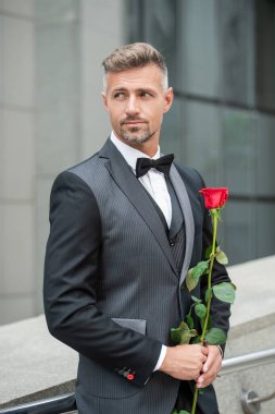 Nişan fikri. Yakışıklı smokinli adam nişanı kutluyor. Nişan için gül hediyeli bir adam.