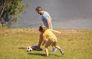 Baba ve oğul arkadaşça bir futbol maçının tadını çıkarıyorlar. Oğlunun babasıyla oynadığı mutlu bir çocukluk. baba ve oğul yaz aktivitesi. Oğlu dışarıda babasıyla vakit geçiriyor. Açık havayı kucaklamak..