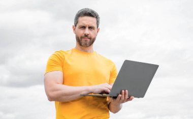 man check email on laptop on sky background.