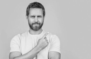 Reklamlara bakan pozitif adam sarı üzerine izole edilmiş bir teklif sunuyor. Adam arka plandaki reklam teklifini işaret ediyor. Stüdyodaki reklam teklifini işaret eden adam. Adam reklam teklifini işaret ediyor..