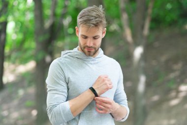 Spor ekipmanlı, formda bir adam akıllı sette zamanı kontrol ediyor. Spor kıyafetleri giymiş bir adamın spor izleme sonuçları. Fitness aleti olan bir koşucu. Fitness için akıllı seğirme.