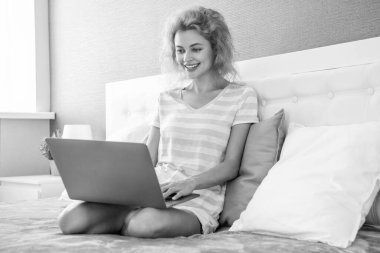 Gülümseyen kız evde dizüstü bilgisayarla çalışıyor. Serbest çalışan bir kız evde çalışıyor. Serbest çalışan biri için ev işi. Dizüstü bilgisayarı olan bir kız..