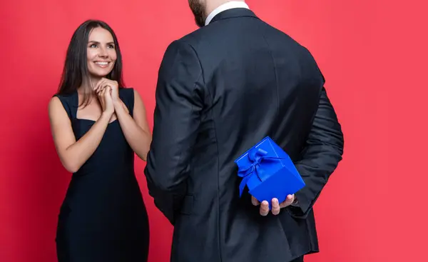 Romantic proposal with gift. Present. Man making proposal to woman. Man give present gift box for Valentines day to woman. Happy Valentines day. Couple in love isolated on red. Proposal moment.