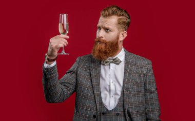 Smokinli şık sakallı şarap garsonu özel bir olayı kırmızı şarap kadehiyle kutluyor..