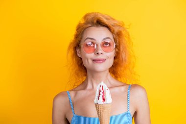 Woman with a cornet ice cream. Delicious gelato in waffle cone in summer. Girl eating ice cream in summer. Happy young woman with delicious ice cream in waffle cone isolated on yellow. Creamy gelato. clipart