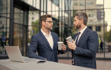 Kahve molasında serbest çalışan iki tüccar. Tüccarlar online olarak dışarıda serbest çalışıyorlar. Ticari tüccarlar dizüstü bilgisayarla serbest çalışıyorlar. Çevrimiçi serbest çalışan tüccarların fotoğrafı.