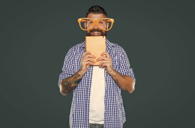 Parti gözlüklü komik sakallı adam elinde kitap tutuyor..