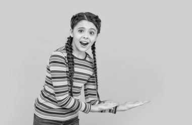 Çocukluk kavramı. Çocukluğunda sarı arka planda izole edilmiş, örgülü genç bir kız. Stüdyoda saçları örgülü genç bir kızın çocukluğu. Genç bir kızın fotoğrafı. Genç kızın çocukluk stüdyosu..