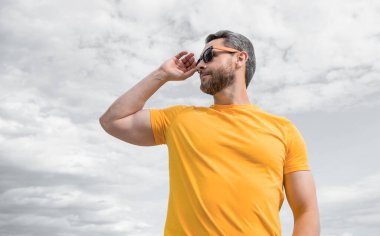 guy wearing yellow shirt and sunglasses outdoor on sky background.