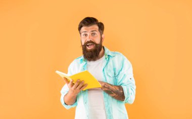 surprised guy reading notebook on yellow background, surprise.