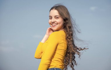 teen girl with cheerful face on sky background.