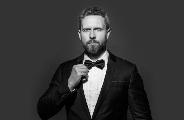Stüdyoda resmi kıyafet. Formalite giymiş bir adamın portresi. Adam resmi smokin giyer. Formalite icabı smokinli adam kırmızı arka planda izole edilmiş..