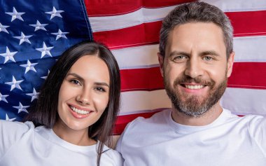 Amerikan mutlu çifti Bağımsızlık Günü 'nde. Amerikan çifti Bağımsızlık Günü ruhunu bayraklarla kucaklıyor. Bağımsızlık Günü tatili. Amerikan bayrağı taşıyan çift. Bağımsızlığı onurlandıran vatansever çift.