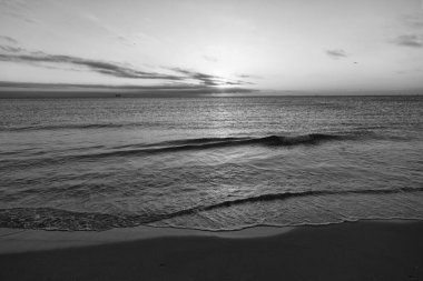 Yaz plajında deniz suyuyla birlikte gün batımı manzarası..