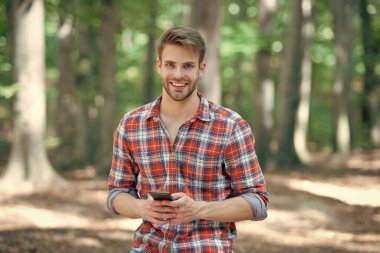 Kareli tişörtlü genç yakışıklı dışarıda telefonda blog yazıyor..