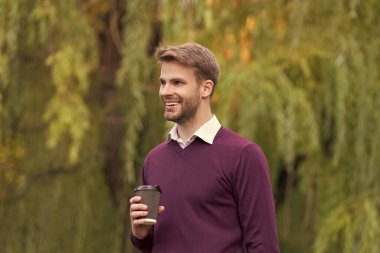 Genç yakışıklı adam sabah kahvesini dışarıda içtiği için mutlu..