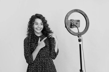 Uzun kıvırcık saçlı gülümseyen çocuk blog için video yapıyor.