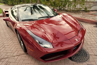 Miami Beach, Florida USA - April 18, 2021: red Ferrari 488 GTB with palm shade, corner view high angle.