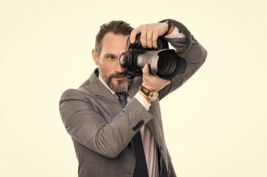 Kameralı iş fotoğrafçısı. Gazeteci, beyazın üstünde tek başına fotoğraf çekiyor. Paparazzi fotoğrafçı. İş adamı fotoğraf makinesini tutar. Takım elbiseli foto muhabiri. fotoğraf muhabiri.