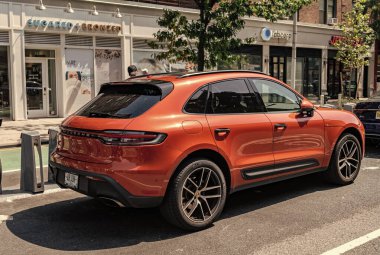 New York City, ABD - 05 Ağustos 2023 Porsche Macan T SUV Yakut kırmızı araç yan ve arka görüş, park.