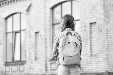 Okul eğitimine dışarıdan bakan genç bir kız. Dışarıda genç bir kızın okul eğitimi var. Sokaktaki genç kız için okul eğitimi. Okul eğitiminin fotoğrafı. Sırt çantalı genç bir kız..