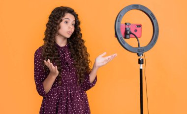 şaşırmış kıvırcık saçlı çocuk blog için video yapıyor.