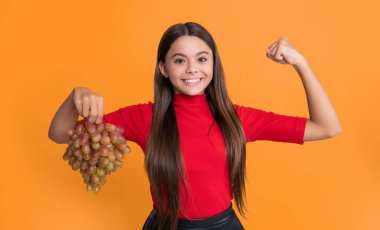 Güçlü çocuk sarı arka planda taze üzüm tutar..