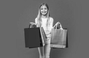 Arka planda alışveriş yapan gülümseyen genç kız. Alışveriş yapan genç bir kızın fotoğrafı. Alışverişi olan genç bir kız mor renkte izole edilmiş. Stüdyoda alışveriş yapan genç kız..