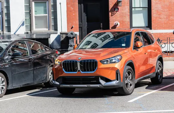stock image New York City, USA - March 31, 2024: 2023 BMW X1 luxury orange car parked outdoor, corner view.