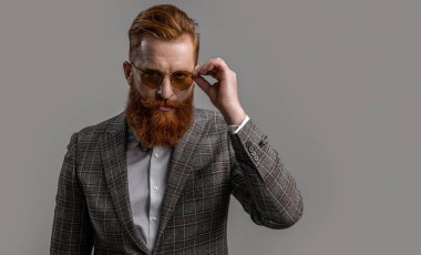 Smokinli, sakallı, şık erkek giyimli, takım elbiseli ve papyonlu bir adam. Gri, fotokopi alanında izole edilmiş..