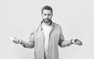 Stüdyonun arka planında cüzdanı olmayan, omuz silkmiş bir adam. Stüdyoda cüzdanı olmayan bir adam. Elinde cüzdanı olan parasız bir adam. Cüzdanlı parasız bir adamın fotoğrafı..